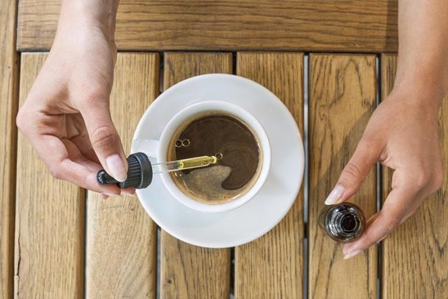 CBD-for-Stress-Blog-Image-OFW image of person putting cbd oil in coffee