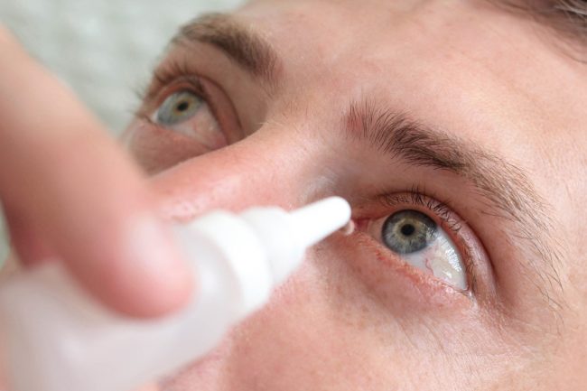 Man drops eye drops install lenses.